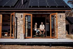 two people sitting on chairs in front of a house with solar panels