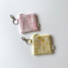 two small purses sitting next to each other on a white surface with keychains