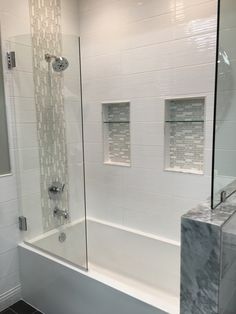 a bathroom with a glass shower door next to a sink and bathtub in it