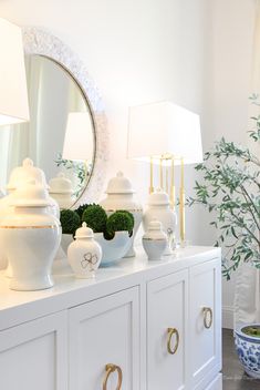 a white dresser topped with vases and lamps