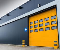 a yellow garage door with an arrow painted on the side and another blue sign in front