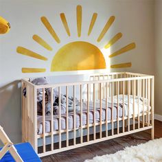 a baby's room with a crib and sun decal on the wall