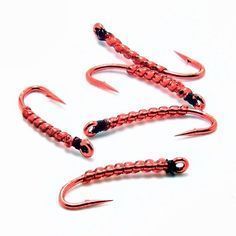 three red fishing lures with black hooks on white background, close up view from above