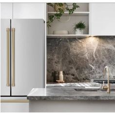 a kitchen with white cabinets and marble counter tops, gold handles on the faucet