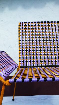 a purple and yellow chair sitting on top of a white floor next to a wall