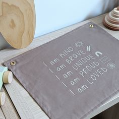 a table with a wooden toy on it next to a brown towel that says, i am kind of broke i am unique i am proud i am loved