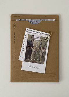 an old photo hanging from a clipboard on a white wall next to a brown envelope