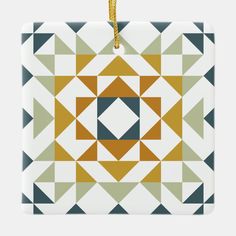 a square ornament with an orange and blue geometric design on the front, hanging from a cord