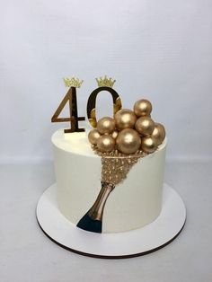 a white cake with gold decorations and the number 40 on it's top tier