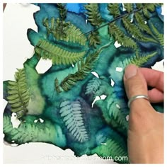 someone is painting leaves on paper with watercolors in the shape of trees and ferns