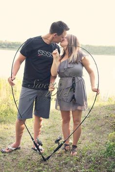 a man and woman standing next to each other in front of a body of water