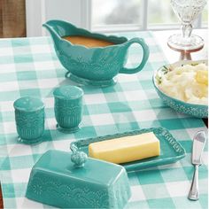 a table topped with green dishes and plates filled with food on top of a checkered table cloth