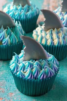 several cupcakes with blue frosting and white icing topped with shark fin shapes