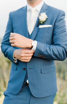 a man in a blue suit and white shirt is holding his hand on his lapel