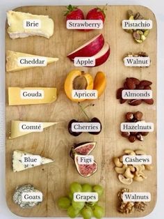 a wooden cutting board topped with lots of different types of cheeses and fruits on it