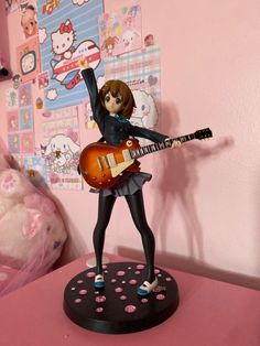 a statue of a girl with a guitar on a table in front of a pink wall