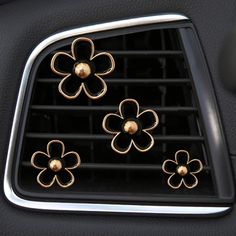 four metal flowers on the center console of a car with air vents in the background