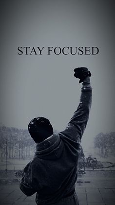 a man raising his arms in the air with words that say stay focused above him