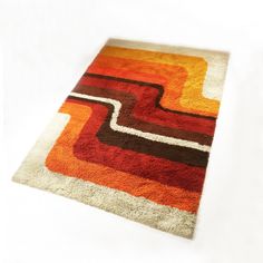 an orange, brown and white rug on a white floor with no one in it