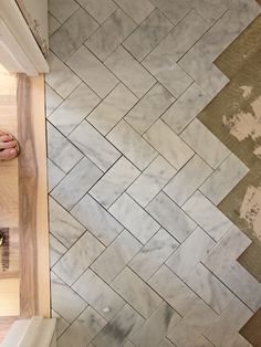 a person standing on a wooden floor next to a tiled wall and counter top area