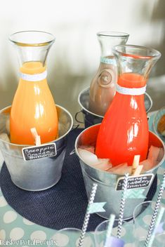 three metal containers with drinks in them on a table