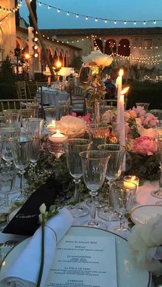 the table is set with wine glasses, silverware and candles for an elegant dinner