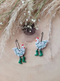 two little chickens are hanging from hooks on a piece of wood