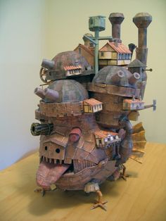 a sculpture made out of cardboard and other items on top of a wooden table next to a wall