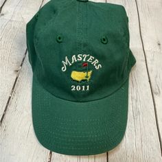 a green hat sitting on top of a white wooden floor with the word masters 2011 embroidered on it