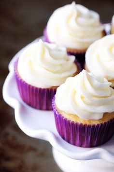 several cupcakes with white frosting on a plate