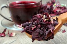 a wooden spoon filled with red cabbage next to a cup of tea