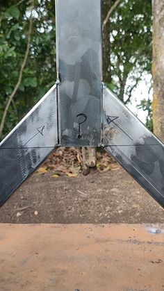 an upside down metal object with trees in the background