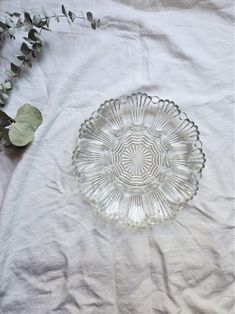 a glass plate sitting on top of a white table cloth next to a green plant