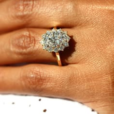 a woman's hand with a diamond ring on top of her finger and an engagement band