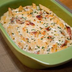 a green casserole dish filled with pasta and cheese, garnished with parsley