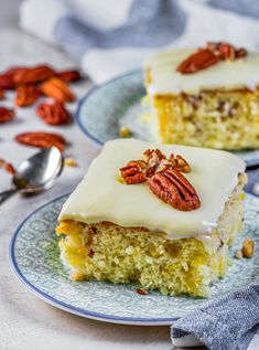 two slices of carrot cake with cream cheese frosting and pecans on the side