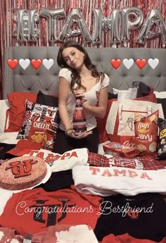 a woman sitting on top of a bed with lots of red and white items in front of her