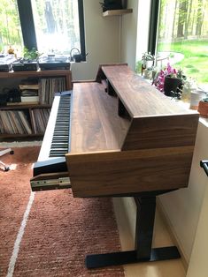 a wooden piano sitting in front of a window