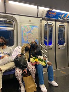 three people sitting on a subway train with masks covering their faces and holding flowers in front of them