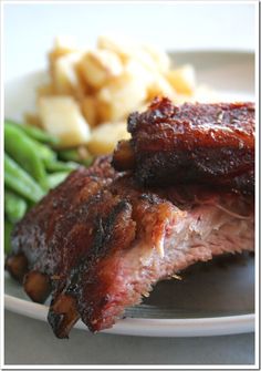 two pieces of meat on a plate with green beans and potatoes