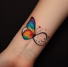 a colorful butterfly tattoo on the wrist with stars and swirls around it's wings