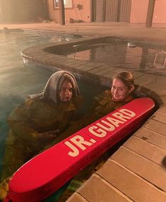 two people sitting in a pool with a surfboard on their back and the words jr guard written on it