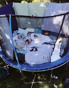 a baby is laying in a trampoline with clothes on the ground next to it