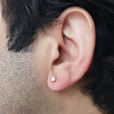 a man with black hair wearing a white diamond studded earring on his left side