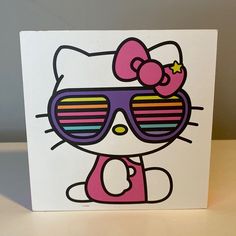 a hello kitty card with sunglasses and a bow on the front, sitting on a table