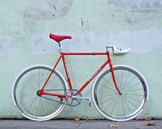 a red and white bicycle leaning against a wall