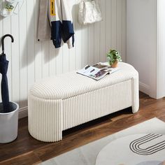 a white bench sitting on top of a hard wood floor next to a potted plant