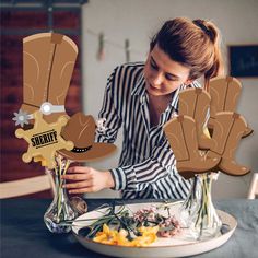 a woman arranging flowers in vases on top of a table with paper cutouts