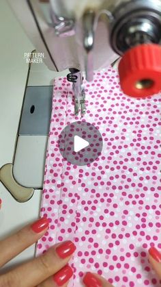 someone is using a sewing machine to sew polka dots on a pink table cloth