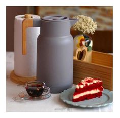 a piece of red velvet cake on a plate next to a water bottle and cup